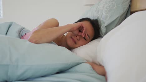 mujer asiática acostada en la cama, despertando por la mañana