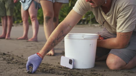 joven caucásico liberando al bebé tortuga joven en el agua del océano en una playa de arena tropical