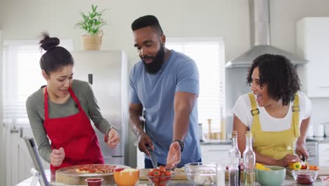 Diverse-male-and-female-friends-cooking-in-kitchen-in-slow-motion