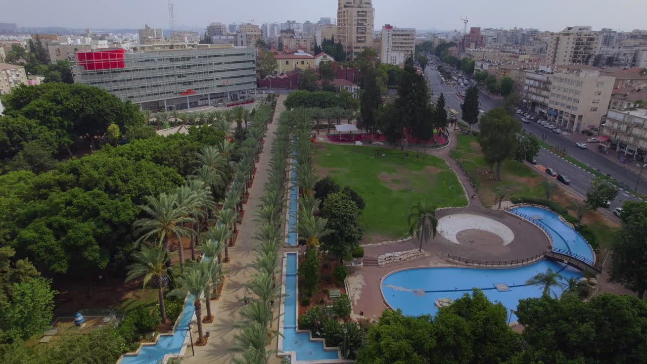 gan hamoshava en rishon lezion en un día de verano con las piscinas, la avenida de las palmeras y los céspedes públicos