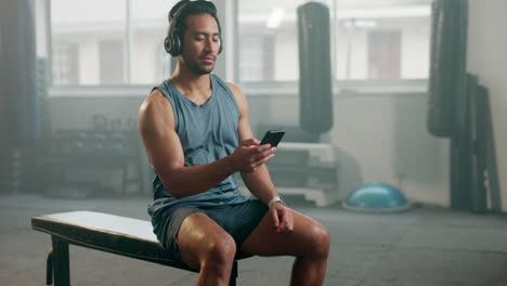 Fitness,-phone-and-a-man-with-headphones-at-gym