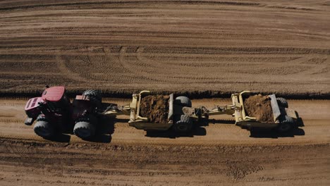 aerial view of a red tractor pulling loads of dirt, preparing the fields for the upcoming season