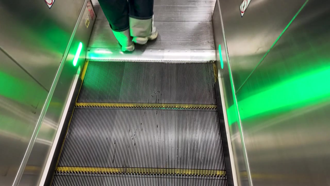 Højvinkelbillede af en person, der kører på en rulletrappe i et transitknudepunkt i Bangkok
