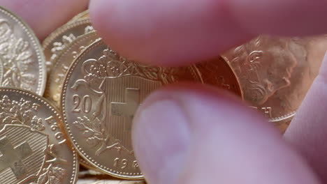 macro shot of finger touching golden twenty franc coins