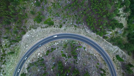 top-down aerial shot of a winding mountain road curving through the forest