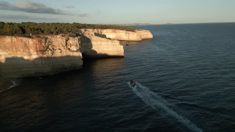 Wide-Drone-Video-of-a-Boat-Approaching-a-Cave-on-the-Coast-of-the-Algarve,-Portugal