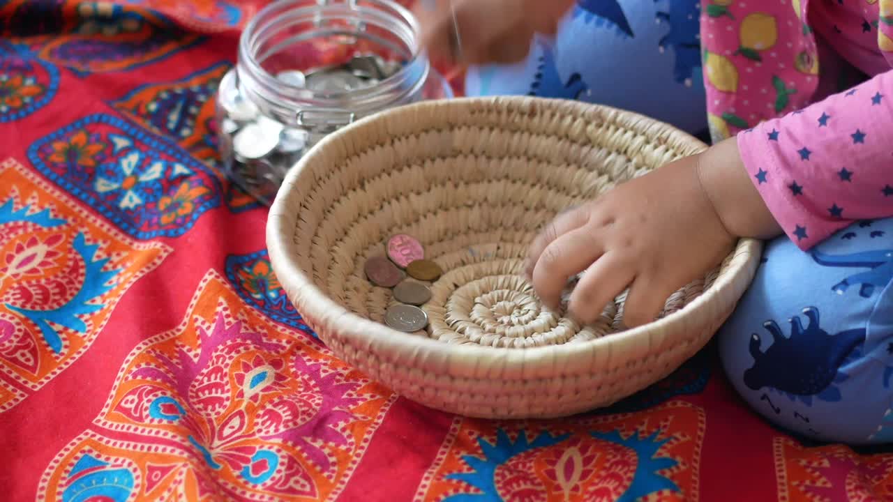 바닥에 앉아 있는 어린 소녀의 저축에 대한 동전 어리