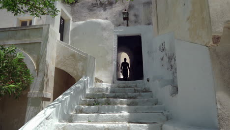 a man descends the steps from the yard of a house through an arch