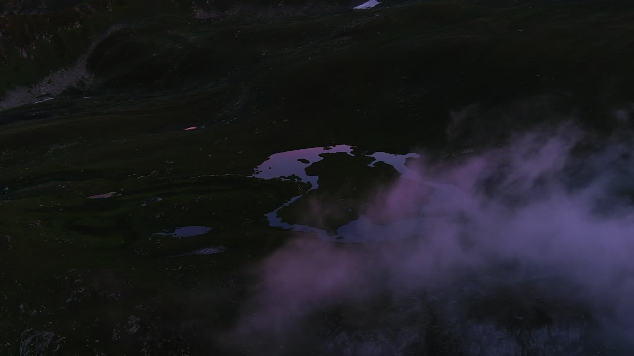 Close-Up Aerial Shot of Clouds Above Mountains with Reflective Waters (High-Res Footage)