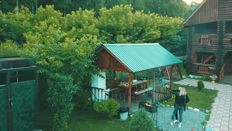 aerial view young guy with a girl is making a selfie near a summer house in the mountains