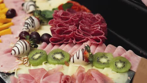 Charcuterie-board-with-cooked,-cured-or-smoked-sausages,-fruits-and-cheeses