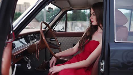 woman in a red dress inside a vintage car