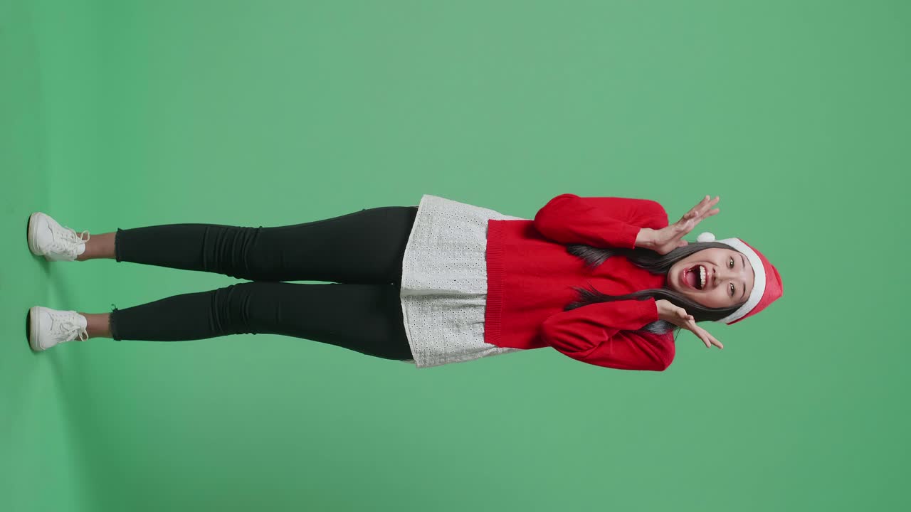Woman wearing Santa hat and expressing excitement.