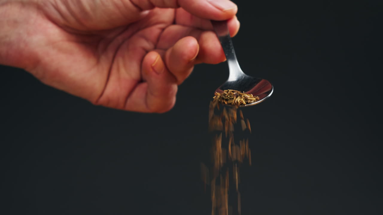 Cumin or jeera seeds on spoon close-up. Seasoning cumin or jeera. Spice for food. High quality 4k footage