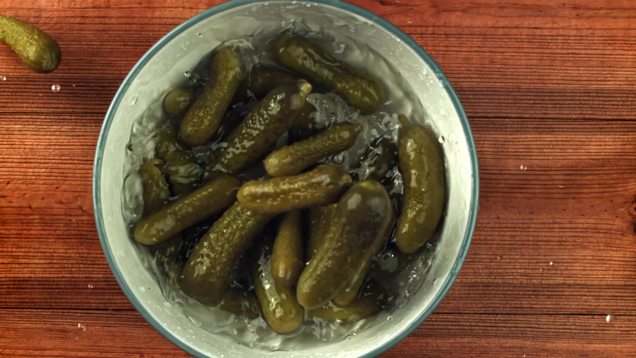 Cetrioli sottaceto che cadono in una ciotola al rallentatore