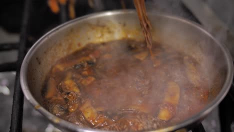 adding fried meat to boiling ragout,close up