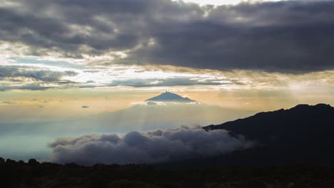 asombrosa puesta de sol con rayos de luz que alcanzan su punto máximo a través de las nubes sobre el monte meru, visto desde el campamento de shira en el monte kilimanjaro en tanzania