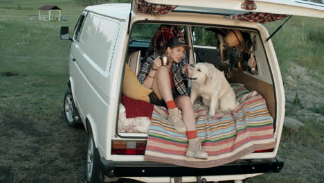 woman and dog sitting in camper van with opened door