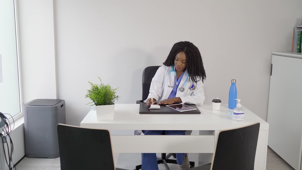 Smiling African American doctor writing in notebook