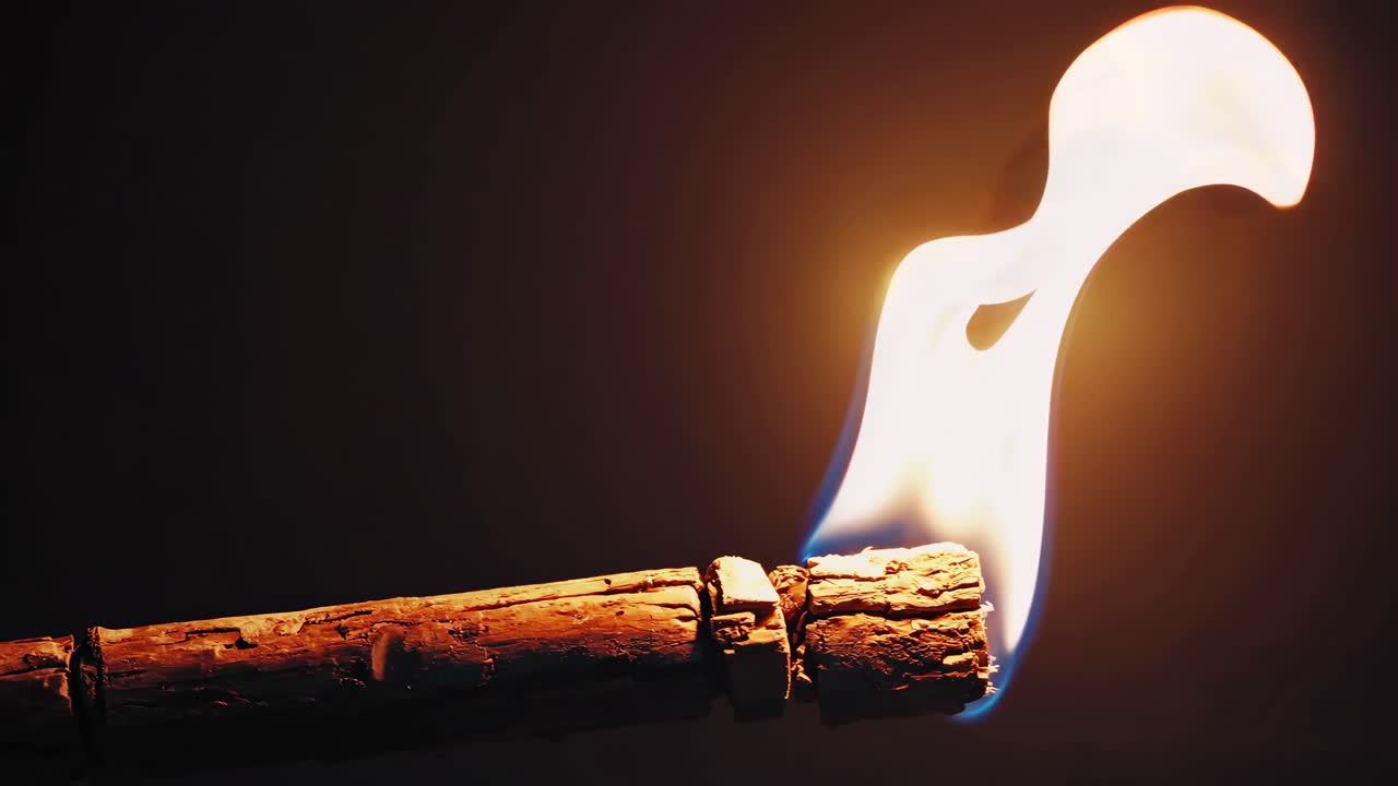 Close-up, low-angle shot of a torch with a flickering flame against a dark background
