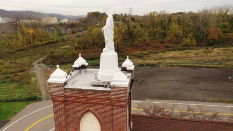 An-aerial-view-of-a-statue-of-the-Virgin-Mary-on-top-of-a-Catholic-Church-in-upstate,-NY