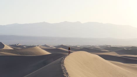 Ultra-slow-motion-shot-of-woman-walking-on-sand-dune-in-the-desert-in-Death-Valley-National-Park-in-California,-USA