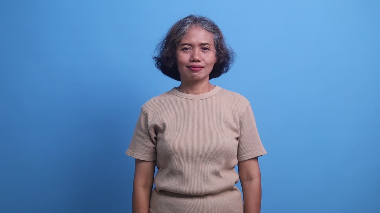 Middle age Asian woman standing confidently, covering one eye with hand