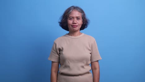 middle age asian woman standing confidently, covering one eye with hand