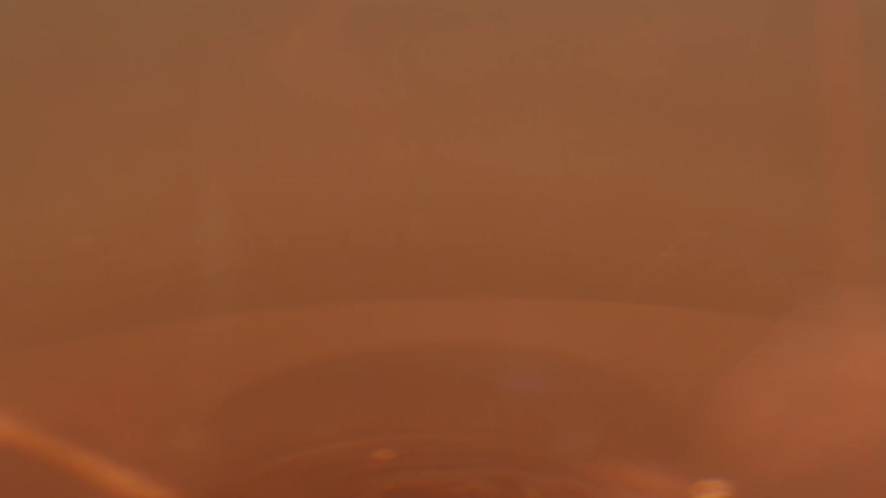 Orange or white wine bottle and glass against a sunset in a peaceful vineyard, pouring of ecological natural wine.