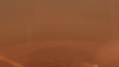 orange or white wine bottle and glass against a sunset in a peaceful vineyard, pouring of ecological natural wine.