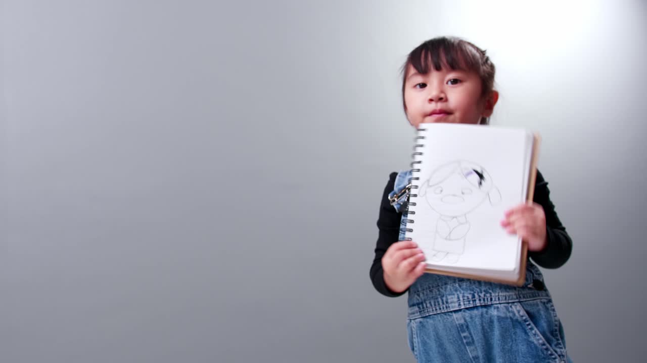 그녀가 그린 그림이 있는 공책을 보여주는 아이