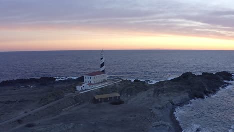 golden hour glow on favaritx lighthouse in menorca, spain