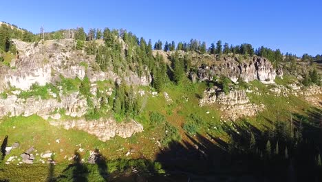 Slow-sliding-shot-of-rugged-canyon-cliffs-above-a-pine-forest