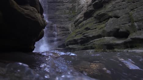 Tiefwinkelansicht-Des-Talflusses-Und-Des-Wasserfalls-In-Der-Ferne,-Umgeben-Von-Stein