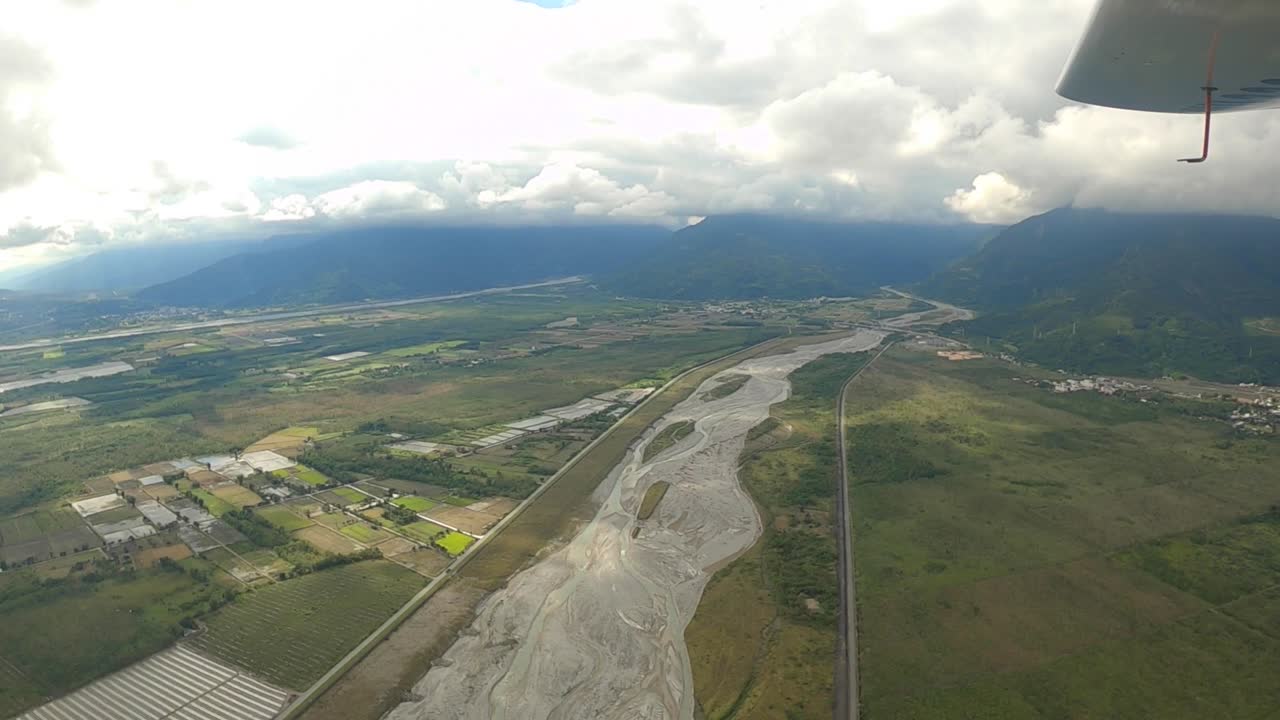 volando sobre el lecho seco del río cerca de tierras agrícolas y montañas