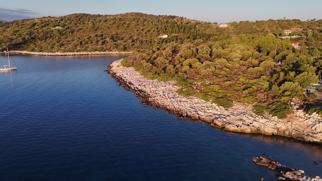 Kastos Island,aerial view pan right panoramic view of the green island overseeing the wind mill cafe and the harbor on a sunny day.Lot of boats at the town quay and on anchor