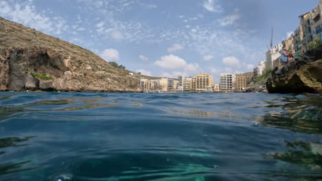 A-view-at-water-level-between-the-rocks-towards-a-town-on-the-island-of-Malta