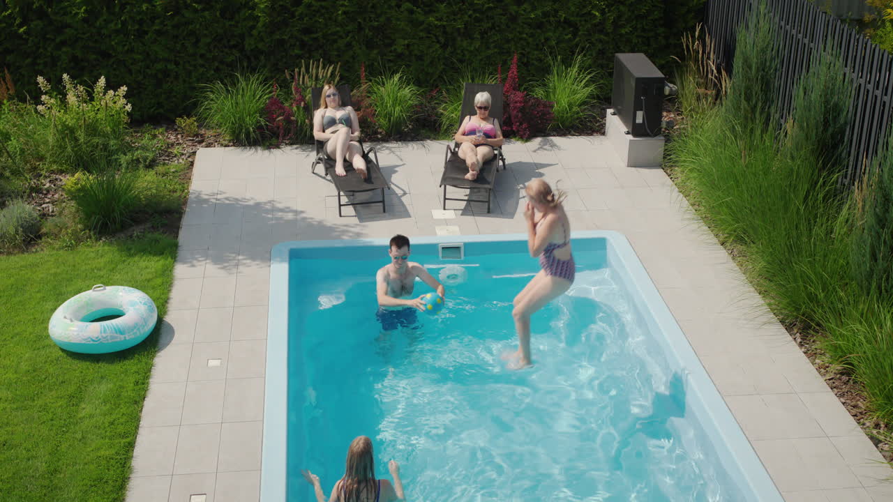 En kvinde hopper i poolen. Familieferie ved poolen i baghaven til en lille villa.