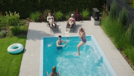 una mujer salta a la piscina. vacaciones familiares junto a la piscina en el patio trasero de una pequeña villa