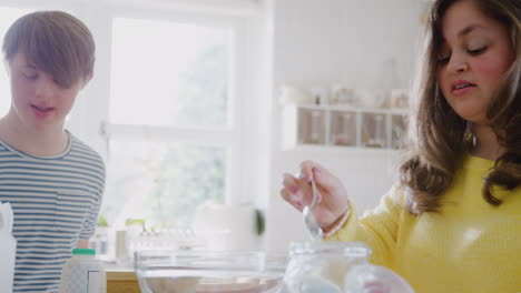 pareja joven con síndrome de down midiendo ingredientes para hornear pastel en la cocina en casa