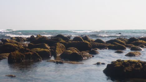 rocks in the beach with small waves reaching the coast