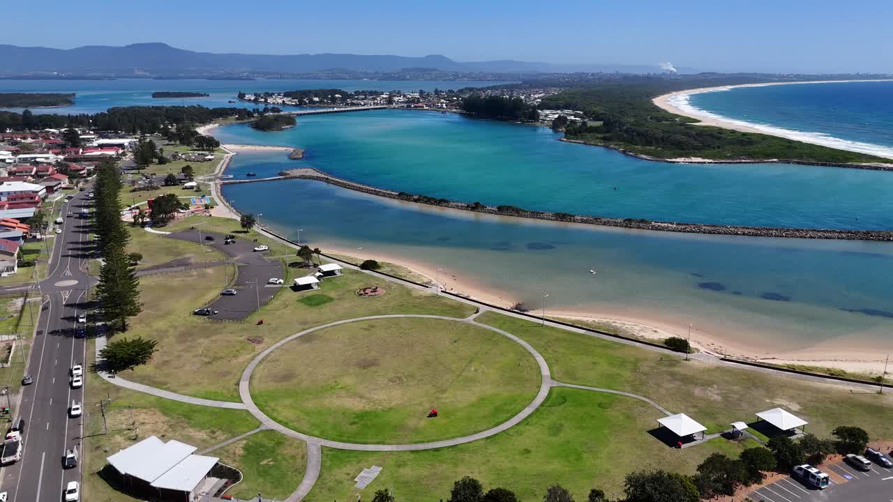 Drone in orbita media sopra il parco Windang foreshore che mostra prati verdi, costa e acqua calma, sentiero pedonale circolare
