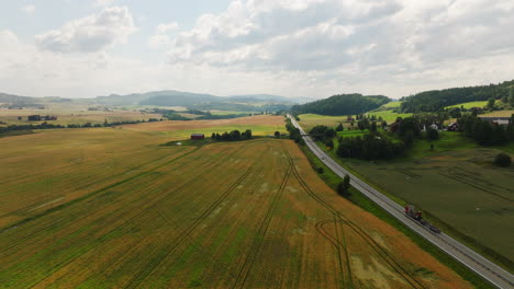 vast wheat fields next to highway e6 with traffic in norway, aerial dolly