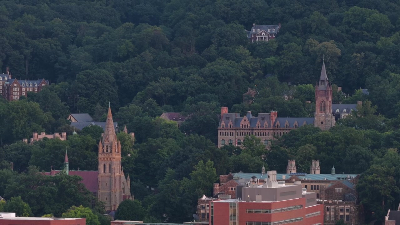 Guglie gotiche e torri in pietra si ergono attraverso il fianco della collina boscosa, edifici universitari storici e il campanile della chiesa si raggruppano tra le cime degli alberi verdi a Betlemme, Pennsylvania. Ampia ripresa aerea con drone