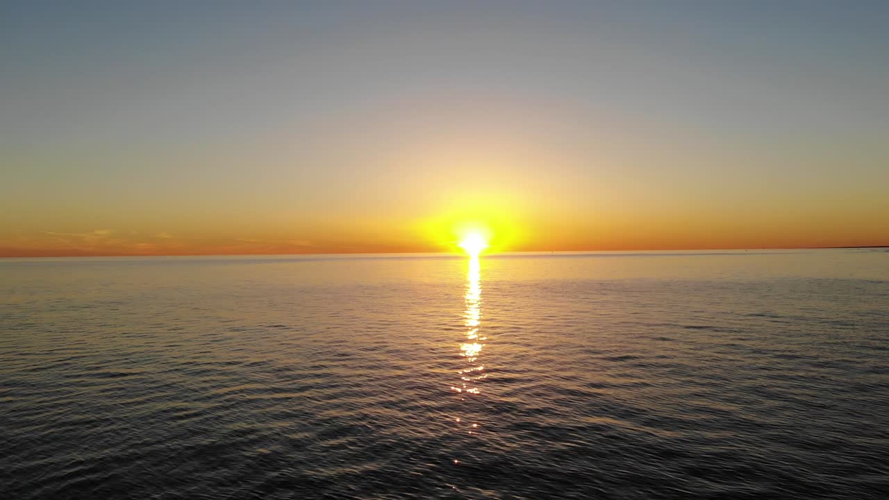 일몰이 내려다보이는 바다 위로 낮게 날아가는 패닝 시네마틱 공중 드론