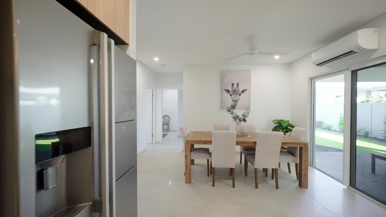 vista interior moderna de una cocina de exhibición que conduce a un área de lavandería, con gabinetes elegantes, encimeras y elementos de diseño contemporáneo