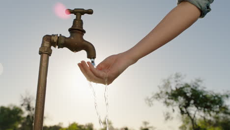 Bäuerin-Wäscht-Sich-Die-Hände-Unter-Leitungswasser-Auf-Einem-Ländlichen-Bauernhof-Mit-Süßwasser,-Das-Aus-Dem-Wasserhahn-Fließt,-Während-Die-Nachmittagssonne-Aufflackert