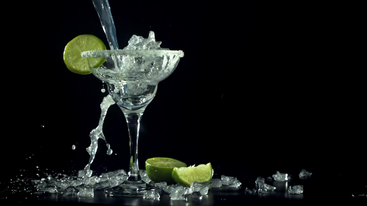 Versamento al rallentatore di cocktail Margarita in un bicchiere bordato di sale