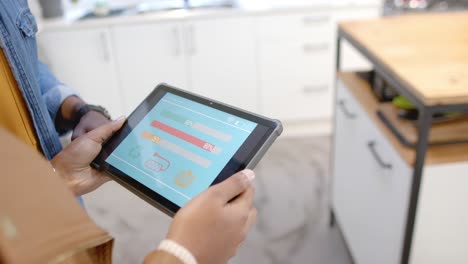 hands of african american couple using tablet with smart home interface in kitchen, slow motion