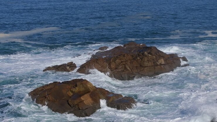 Onde marine che si infrangono sugli scogli a Praia da Salsa, Arteixo, A Coruña, Galizia, Spagna. Ripresa aerea